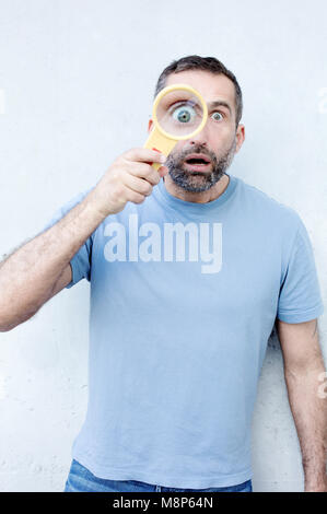 Funny portrait of handsome homme barbu tenant une loupe Banque D'Images