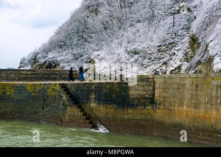 18/03/2018 Charlestown, Cornwall, UK, Editorial : inconnu des membres du public en marchant le long du mur du port de Charlestown avec falaises couvertes de neige Banque D'Images