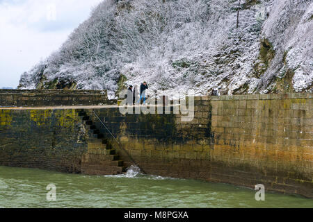 18/03/2018 Charlestown, Cornwall, UK, Editorial : inconnu des membres du public en marchant le long du mur du port de Charlestown avec falaises couvertes de neige Banque D'Images