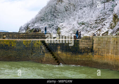 18/03/2018 Charlestown, Cornwall, UK, Editorial : inconnu des membres du public en marchant le long du mur du port de Charlestown avec falaises couvertes de neige Banque D'Images