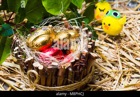 Les bonbons oeufs au nid en osier et toy, poulet de Pâques Banque D'Images