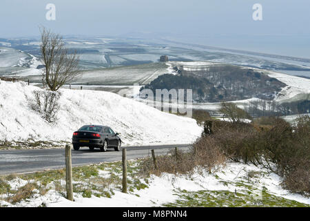 Abbotsbury, Dorset, UK. 19 mars 2018. Météo britannique. Une voiture conduit par un transport de la neige qui borde la route côtière B3157 sur la colline près de Abbotsbury Abbotsbury dans Dorset sur une froide journée glaciale. Dans la distance est l'emblème de la Chapelle Sainte Catherine. Crédit photo : Graham Hunt/Alamy Live News. Banque D'Images