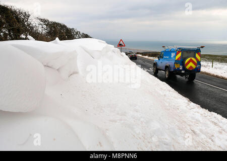 Abbotsbury, Dorset, UK. 19 mars 2018. Météo britannique. Une voiture conduit par un énorme snow drift qui borde la côte de la route B3157 en haut de la colline près d'Abbotsbury Abbotsbury dans Dorset sur une froide journée glaciale. Crédit photo : Graham Hunt/Alamy Live News. Banque D'Images