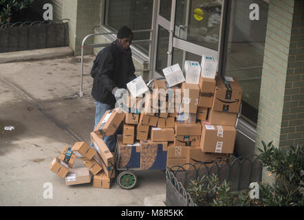 Un livreur de Lasership avec son chariot chargé d'achats de l'aime de Amazon, tablier bleu, et d'autres sortes ses livraisons à un immeuble le quartier de Chelsea, New York, le vendredi 9 mars 2018 . (© Richard B. Levine) Banque D'Images