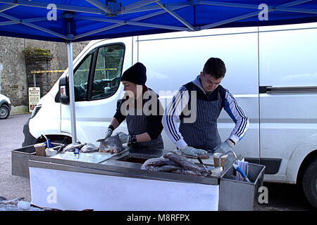 Les jeunes poissons poissonniers l'éviscération du poisson sur leur stand au marché alimentaire hebdomadaire local dans la région de Baltimore, West Cork. Banque D'Images