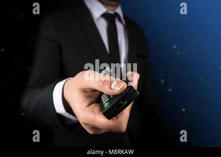 Les entreprises, les gens et la technologie concept - close up of businessman avec télécommande sur fond noir Banque D'Images