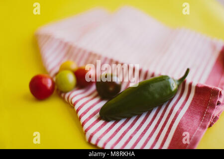 Close-up de piment jalapeno et tomates cerise sur le textile sur fond jaune Banque D'Images