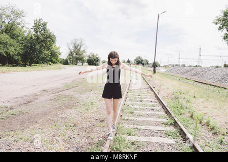 Toute la longueur de young woman with arms outstretched marche sur la voie de chemin de fer Banque D'Images