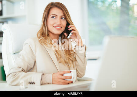 Jeune femme sérieuse réfléchie perdue dans ses pensées en utilisant smartphone, réfléchir au travail, question tenue tasse de café. Banque D'Images