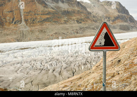Signe de route avec mise en garde contre les chutes de pierres près de glacier dans les Alpes Suisses Banque D'Images