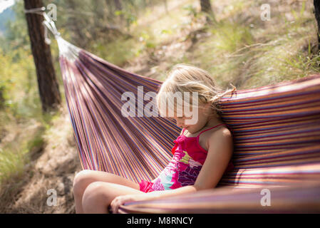 Girl sitting in hammock at forest Banque D'Images