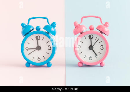 Deux petits réveils sur fond rose et bleu pastel. Les heures de travail concept minimal. Banque D'Images