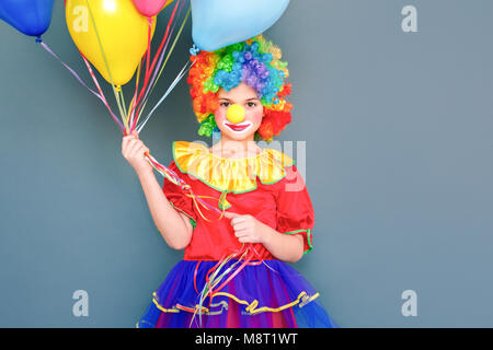 Clown Girl holding beaucoup de ballons se préparer pour le carnaval. Studio shot, isolé sur fond gris Banque D'Images