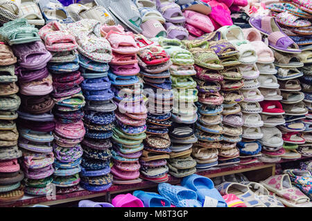 YANJIXI, Jilin, Chine - 9 mars, 2018 : chaussons et sandales sont montré vendus sont disposés et empilés dans un beau fond tacheté dans le vêtement Banque D'Images