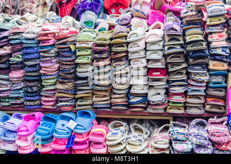 YANJIXI, Jilin, Chine - 9 mars, 2018 : chaussons et sandales sont montré vendus sont disposés et empilés dans un beau fond tacheté dans le vêtement Banque D'Images