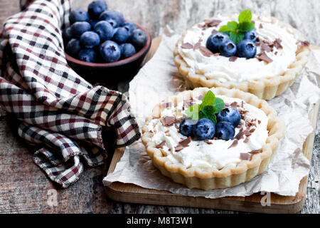 Délicieux avec de la crème et des tartes aux bleuets frais sur table en bois Banque D'Images