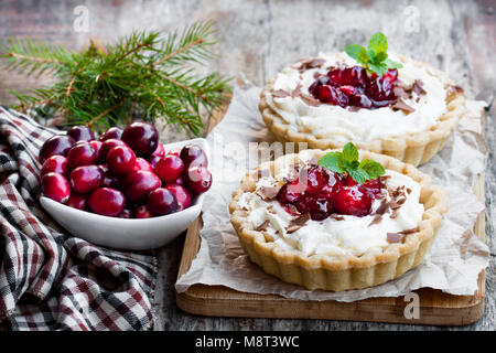 Délicieux avec de la crème fraîche et tartelettes cranberry sur table en bois. Dessert de Noël. Banque D'Images