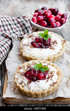 Délicieux avec de la crème fraîche et tartelettes cranberry sur table en bois. Dessert de Noël. Banque D'Images