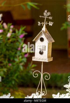 Cabane blanc décoratif dans un jardin de fleurs avec girouette classique sur le dessus Banque D'Images