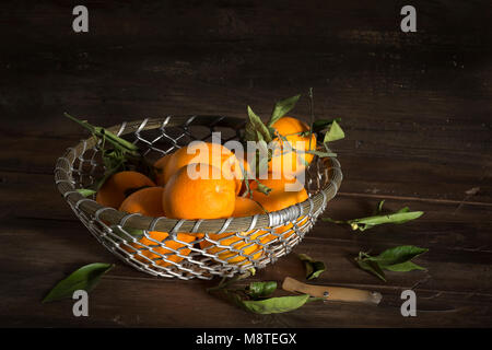 Groupe d'oranges dans un panier métal sur fond de bois Banque D'Images