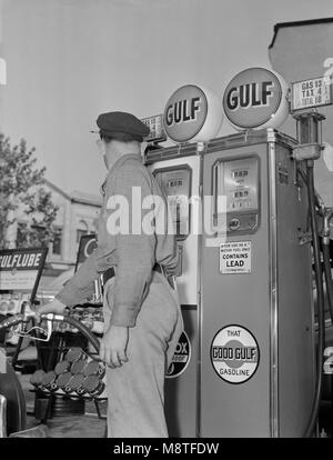 Préposé de station de gaz à effet de pompage tout en gardant un œil sur la jauge lors de rationnement de l'essence, USA, Bureau de l'information de guerre, 1940 Banque D'Images