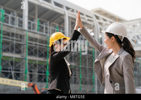 Deux femmes donne-moi cinq architecte à l'autre avec un sourire satisify . À côté de l'emplacement de l'édifice, ils applaudissent les mains avec bonheur. Banque D'Images