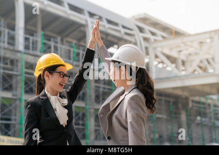 Deux claquements de mains l'ingénieur femme montrant leur bonheur et joyeux pour la réussite de leur projet de conception de bâtiment. Ils ont tous deux portant un grand sourire Banque D'Images