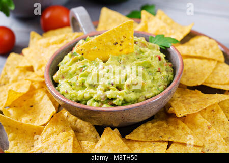 Guacamole avocat, citron vert, tomate, oignon et coriandre, servi avec des nachos - snack traditionnel Mexicain Banque D'Images