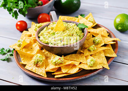 Guacamole avocat, citron vert, tomate, oignon et coriandre, servi avec des nachos - snack traditionnel Mexicain Banque D'Images