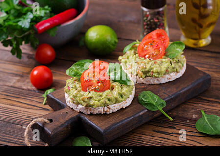 Petit déjeuner sain. Pain croustillant sandwich avec guacamole et tomates sur un fond de bois. Banque D'Images