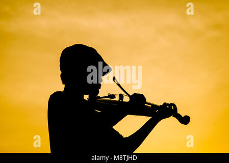 Silhouette garçon à jouer du violon avec soleil. Banque D'Images