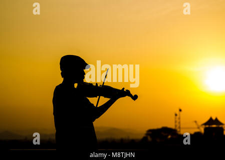 Silhouette garçon à jouer du violon avec soleil. Banque D'Images