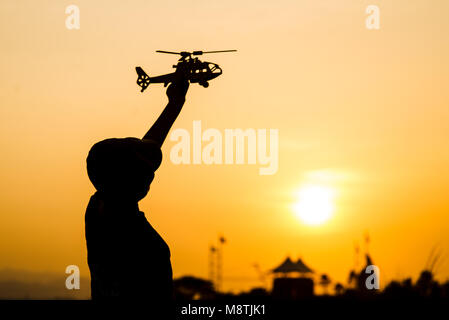 Silhouette Garçon jouant modèle d'hélicoptère avec du soleil. Banque D'Images