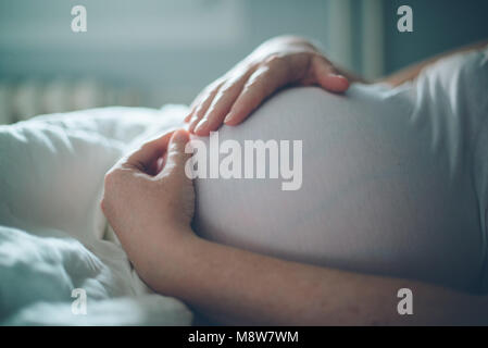 Femme enceinte ventre câlins dans la chambre à la maison juste avant le travail et l'accouchement, selective focus Banque D'Images