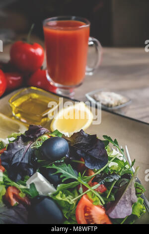 Régime salade pour correction du poids des feuilles de laitue Lollo Rosso salade de cresson, et d'autres herbes vertes avec tomates, olives et fitaki. Close up. Banque D'Images