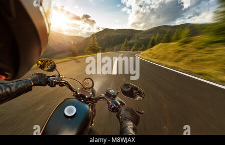 POV de motorbiker maintenant le bar, équitation dans Alpes en beau coucher du soleil Ciel dramatique. Et la liberté de déplacement, activités en plein air Banque D'Images