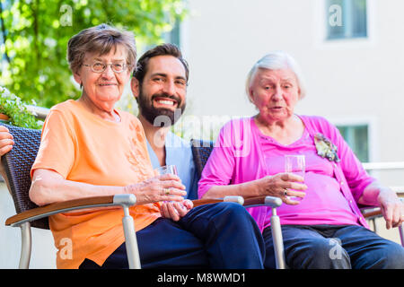 Infirmière de boire du café avec terrasse sur les aînés de la maison de retraite Banque D'Images
