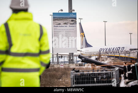 20 mars 2018, l'Allemagne, Frankfurt am Main : un avion de Ryanair (r) stationné à côté d'un signe de la construction de la nouvelle aérogare 3. Photo : Frank Rumpenhorst/dpa Banque D'Images