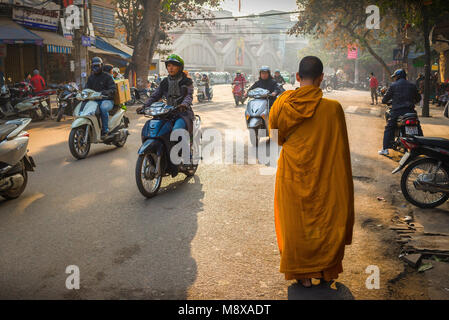 Scène de rue du Vietnam, vue à l'aube d'un jeune moine bouddhiste faisant son chemin à travers le vieux quartier historique dans le centre de Hanoi, Vietnam Banque D'Images