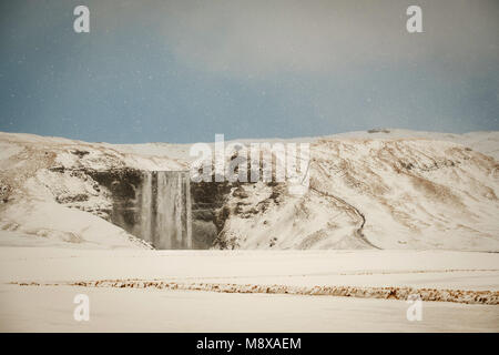 Skogafoss, la grande et belle cascade en Islande au cours de l'hiver. Tempête de neige dans la région de l'Islande près de la célèbre cascade de Skogafoss. Banque D'Images