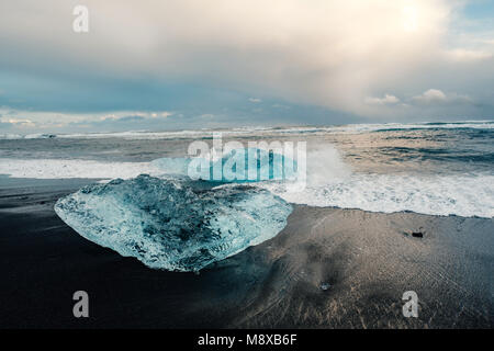 De la glace sur la plage volcanique noire près de glacier Jökulsárlón lagoon, hiver Islande. Détail d'un fragment de glace glaciaire à la magnifique plage de sable noir Banque D'Images