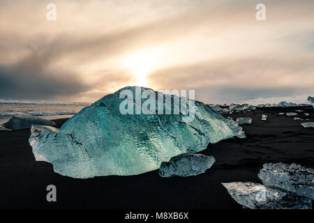 De la glace sur la plage volcanique noire près de glacier Jökulsárlón lagoon, hiver Islande. Détail d'un fragment de glace glaciaire à la magnifique plage de sable noir Banque D'Images