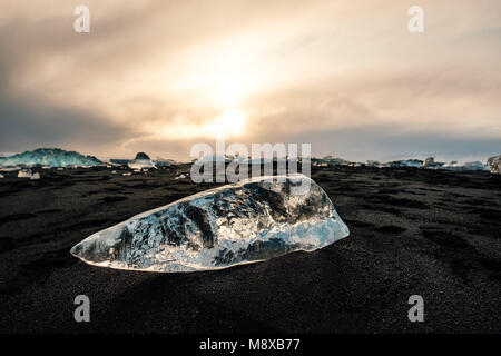 De la glace sur la plage volcanique noire près de glacier Jökulsárlón lagoon, hiver Islande. Détail d'un fragment de glace glaciaire à la magnifique plage de sable noir Banque D'Images