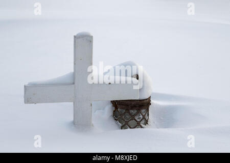 Cimetière en hiver, une petite croix en bois et une lanterne couverte de neige Banque D'Images