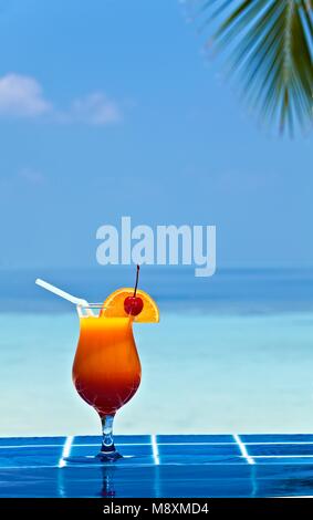 Verre de jus d'orage est sur le bord de piscine fabriqués à partir de carreaux émaillés à l'hôtel tropical, Maldives Banque D'Images