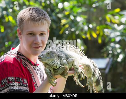 Le jeune homme, l'adolescent est titulaire d'un iguane sur les mains Banque D'Images