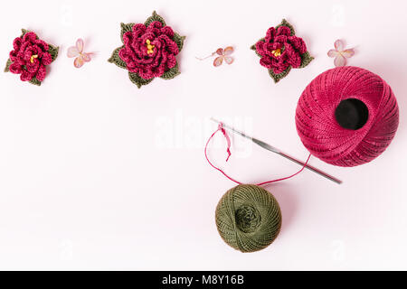 Le rouleau de fil de coton vert et violet et rose au crochet crochet, fleurs, décoration, ornement, Bastet sur fond blanc. Le concept de croch Banque D'Images