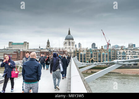 Les gens qui marchent à travers le Millenium Bridge à Londres lors d'une froide journée nuageuse. Banque D'Images