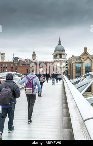 Les gens qui marchent à travers le Millenium Bridge à Londres lors d'une froide journée nuageuse. Banque D'Images