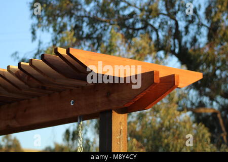 Pergola de jardin au coucher du soleil dans un jardin avec des arbres en arrière-plan. La pergola est faite de cèdre rouge du Pacifique. Banque D'Images